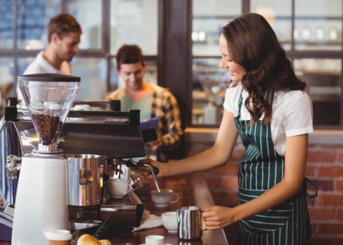 Pretty barista making a cup of coffee at the coffee shop